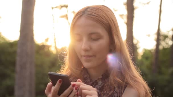 Portrét s úsměvem šťastná dívka pomocí telefonu a při pohledu na fotoaparát — Stock video