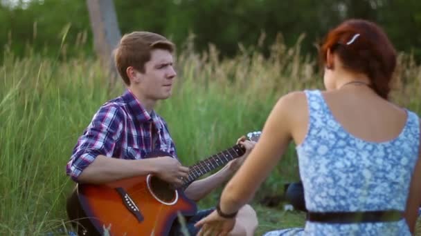 Парень играет на гитаре для своей девушки — стоковое видео