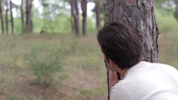 Mann sucht und spioniert einen Hintergrund in der Natur — Stockvideo