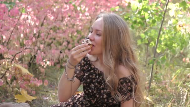 Νεαρά κορίτσια που τρώνε cupcake και χαμόγελο φθινόπωρο — Αρχείο Βίντεο