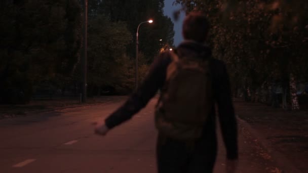 Чоловік влітку вночі, з рюкзаком йде в дорогу — стокове відео