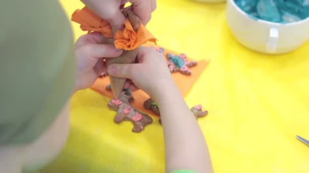 Kleines glückliches Mädchen dekoriert Lebkuchen — Stockvideo
