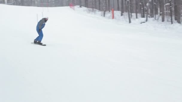 Escorregas de snowboarder masculino na montanha no dia de inverno . — Vídeo de Stock
