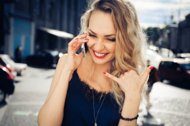 şehrin arka planında poz akıllı telefon ile sarışın kız