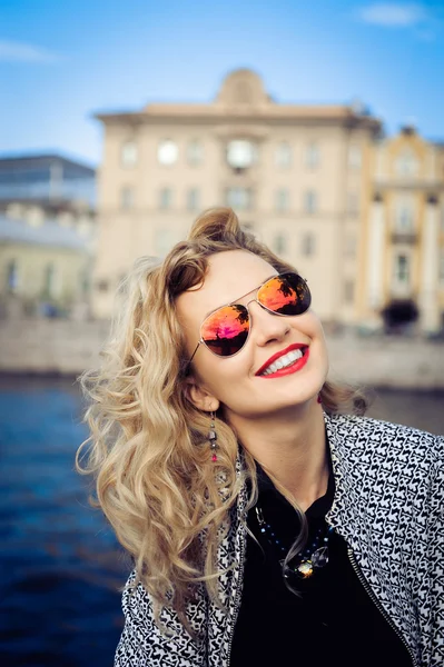 Mladá dívka v sluneční brýle pózuje na pozadí města — Stock fotografie