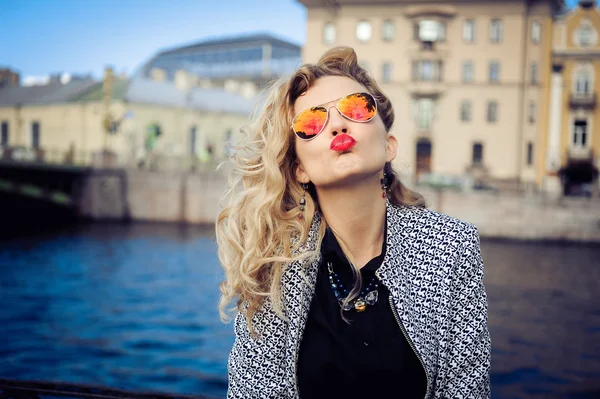 Jong meisje in zonnebril poseren tegen de achtergrond van de stad — Stockfoto
