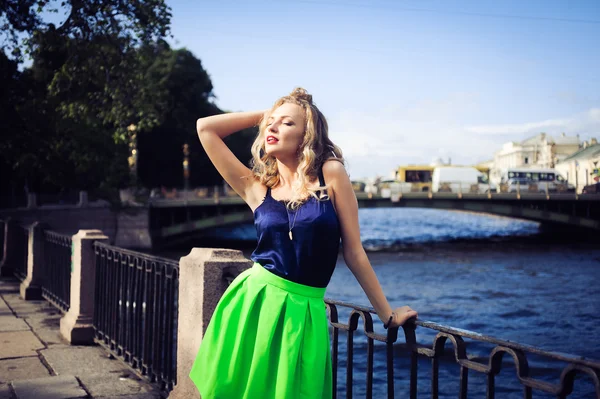Young beautiful blonde girl laughing and posing against the backdrop of the city — Stock Photo, Image