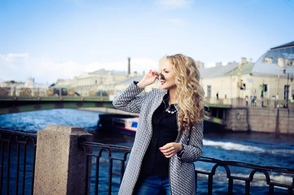 Mooie blonde meisje lachen en poseren tegen de achtergrond van de stad — Stockfoto