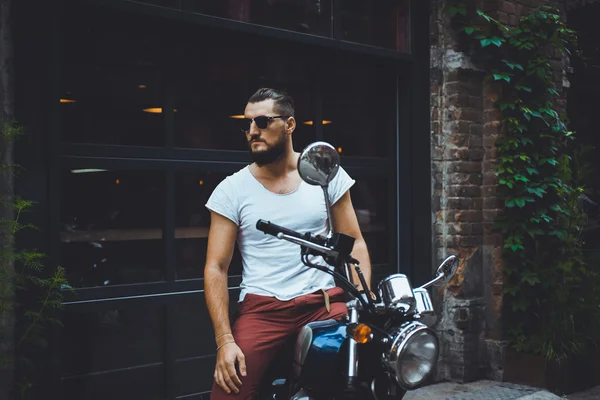 young guy posing sitting on motorcycle