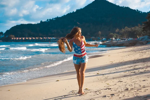 Retrato de una hermosa joven morena con el pelo largo sobre un fondo de mar azul — Foto de Stock