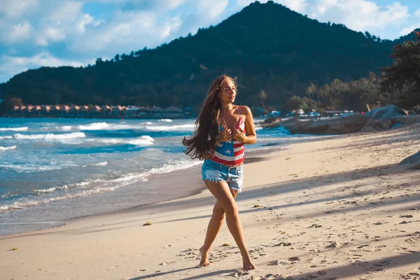 Retrato de una hermosa joven morena con el pelo largo sobre un fondo de mar azul —  Fotos de Stock