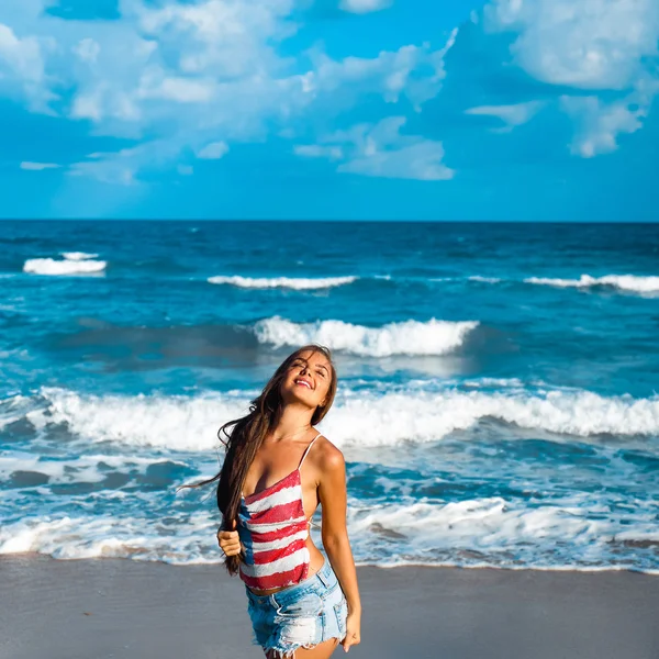 Retrato de una hermosa joven morena con el pelo largo sobre un fondo de mar azul — Foto de Stock