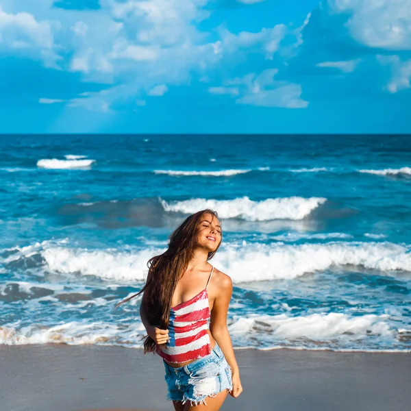 Retrato de una hermosa joven morena con el pelo largo sobre un fondo de mar azul — Foto de Stock