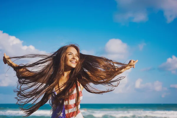 Ritratto di una bella giovane ragazza bruna con i capelli lunghi su uno sfondo di mare blu Foto Stock