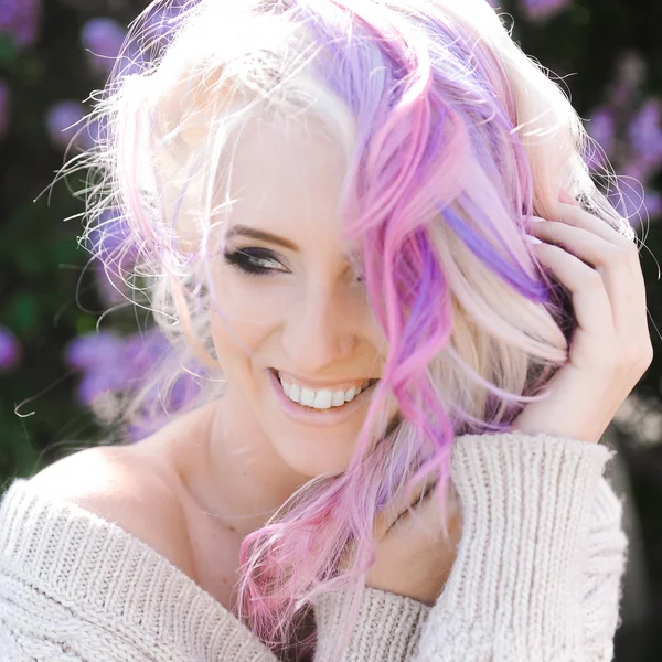 Ragazza bionda hipster con lilla e capelli rosa in posa all'aperto Foto Stock