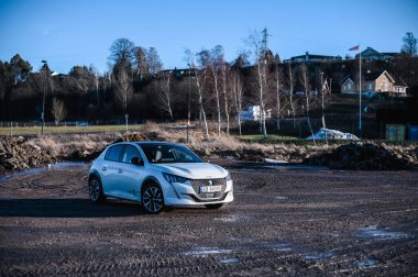 Tnsberg, Norveç - 23 Ocak 2021: inci beyazı elektrikli otomobil Peugeot e-208 GT yeni bir kompakt elektrikli otomobil. Şarj istasyonunda yeni bir araba