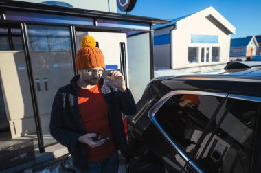 Turuncu şapkalı inek şarj istasyonundaki elektrikli arabayı şarj ediyor..