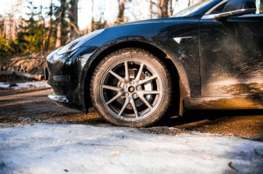 Tonsberg, Norveç - 18 Mart 2021: siyah Tesla modeli 3 Long Range çift motorlu arka planda İskandinav ormanı olan elektrikli bir otomobil..