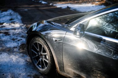 Tonsberg, Norveç - 18 Mart 2021: siyah Tesla modeli 3 Long Range çift motorlu arka planda İskandinav ormanı olan elektrikli bir otomobil..