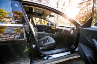 Tonsberg, Norveç - 18 Mart 2021: siyah Tesla modeli 3 Long Range çift motorlu arka planda İskandinav ormanı olan elektrikli bir otomobil..