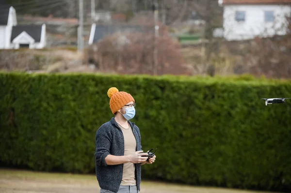 Nerdy guy using  drone for delivery while wearing face mask to avoid corona virus spreading - Technology and industrial concept