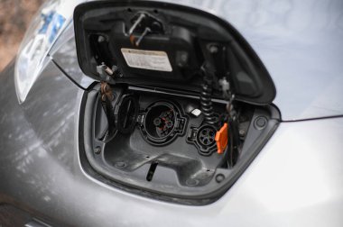 Tonsberg, Norveç - Nisan 06, 2021: Gri gri NISSAN LEAF, C segment elektrikli otomobil. Ormanda güneşli bir günde yeni bir araba.