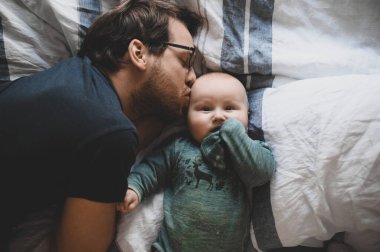 Evde gözlüklü, oğluyla oynayan ve öpüşen çekici bir inek portresi. Sevimli erkek bebek. Mutlu babalar