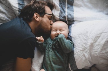 Evde gözlüklü, oğluyla oynayan ve öpüşen çekici bir inek portresi. Sevimli erkek bebek. Mutlu babalar