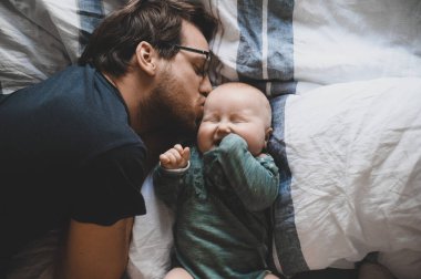 Evde gözlüklü, oğluyla oynayan ve öpüşen çekici bir inek portresi. Sevimli erkek bebek. Mutlu babalar