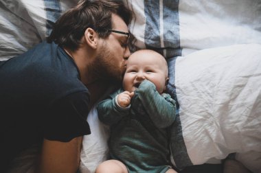 Evde gözlüklü, oğluyla oynayan ve öpüşen çekici bir inek portresi. Sevimli erkek bebek. Mutlu babalar