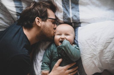 Evde gözlüklü, oğluyla oynayan ve öpüşen çekici bir inek portresi. Sevimli erkek bebek. Mutlu babalar