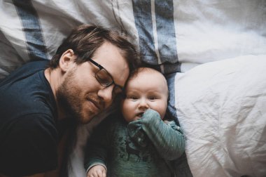 Evde gözlüklü, oğluyla oynayan ve öpüşen çekici bir inek portresi. Sevimli erkek bebek. Mutlu babalar