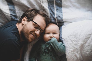 Evde gözlüklü, oğluyla oynayan ve öpüşen çekici bir inek portresi. Sevimli erkek bebek. Mutlu babalar