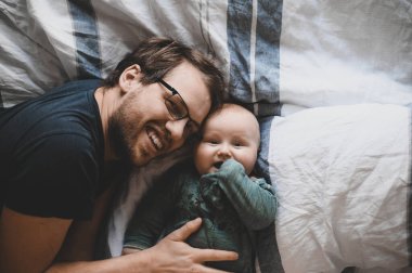 Evde gözlüklü, oğluyla oynayan ve öpüşen çekici bir inek portresi. Sevimli erkek bebek. Mutlu babalar