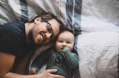 Evde gözlüklü, oğluyla oynayan ve öpüşen çekici bir inek portresi. Sevimli erkek bebek. Mutlu babalar