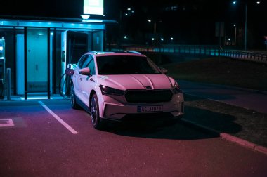 Tonsberg, Norveç - 15 Mayıs 2021: Beyaz Skoda enyaq IV bir SUV elektrikli arabadır. Gece şarj istasyonunda yeni bir araba.