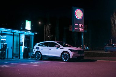 Tonsberg, Norveç - 15 Mayıs 2021: Beyaz Skoda enyaq IV bir SUV elektrikli arabadır. Gece şarj istasyonunda yeni bir araba.