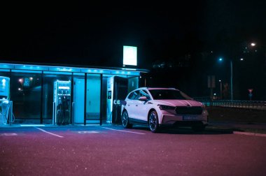 Tonsberg, Norveç - 15 Mayıs 2021: Beyaz Skoda enyaq IV bir SUV elektrikli arabadır. Gece şarj istasyonunda yeni bir araba.