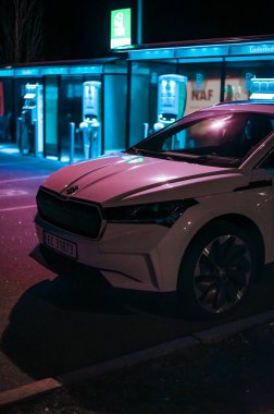 Tonsberg, Norveç - 15 Mayıs 2021: Beyaz Skoda enyaq IV bir SUV elektrikli arabadır. Gece şarj istasyonunda yeni bir araba.