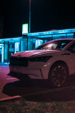 Tonsberg, Norveç - 15 Mayıs 2021: Beyaz Skoda enyaq IV bir SUV elektrikli arabadır. Gece şarj istasyonunda yeni bir araba.