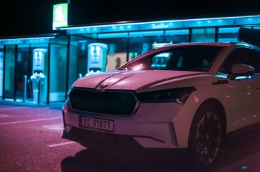 Tonsberg, Norveç - 15 Mayıs 2021: Beyaz Skoda enyaq IV bir SUV elektrikli arabadır. Gece şarj istasyonunda yeni bir araba.