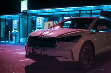 Tonsberg, Norveç - 15 Mayıs 2021: Beyaz Skoda enyaq IV bir SUV elektrikli arabadır. Gece şarj istasyonunda yeni bir araba.