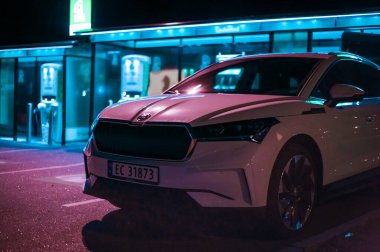 Tonsberg, Norveç - 15 Mayıs 2021: Beyaz Skoda enyaq IV bir SUV elektrikli arabadır. Gece şarj istasyonunda yeni bir araba.