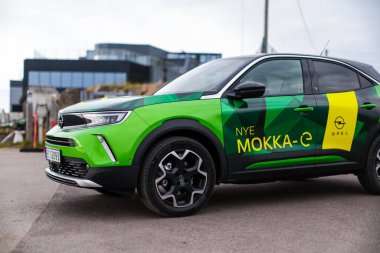 Tonsberg, Norveç - 4 Mayıs 2021: Green Opel Mokka-e elektrikli otomobil. Gece şarj istasyonunda yeni bir araba.