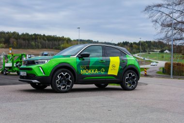 Tonsberg, Norveç - 4 Mayıs 2021: Green Opel Mokka-e elektrikli otomobil. Gece şarj istasyonunda yeni bir araba.