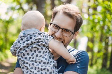 Ormanda gözlüklü çekici bir ineğin portresi bir erkek bebekle yürüyor. Mutlu babalar