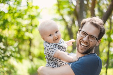 Ormanda gözlüklü çekici bir ineğin portresi bir erkek bebekle yürüyor. Mutlu babalar