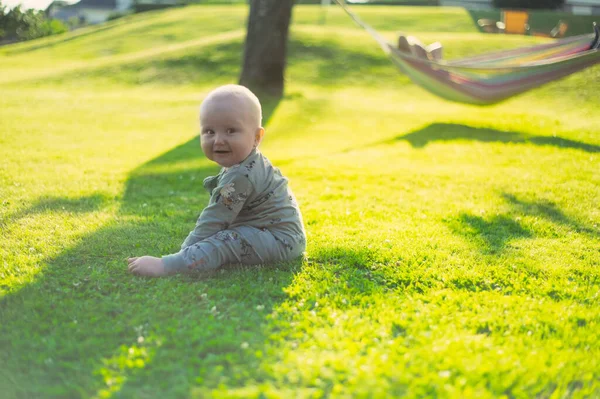 迷人的书呆子男人的肖像 戴着眼镜在公园里与绿色草坪有一个漂亮的日落与一个男婴旁边的吊床 快乐的父爱 — 图库照片