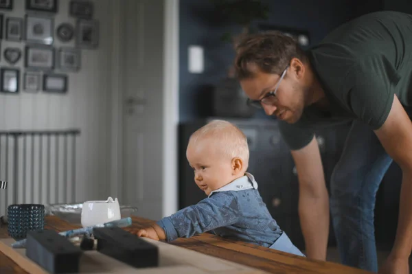 portrait of attractive nerd    with glasses at home  playing with a son. Cute baby boy. Happy fatherhood
