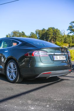 Notteroy, Norveç - 22 Ağustos 2021 Tesla model S P85 + arka planda İskandinav limanı olan elektrikli bir otomobil..